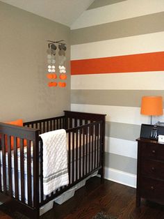 a baby's room is decorated in orange, gray and white