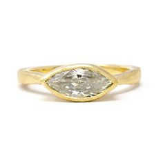 a yellow gold ring with a pear shaped diamond in the center and a thin band around it