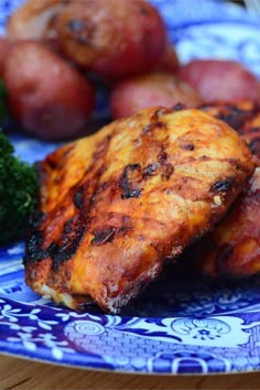 two pieces of grilled chicken on a blue and white plate with broccoli