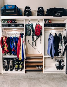 an organized closet with clothes, shoes and backpacks hanging on the wall next to it