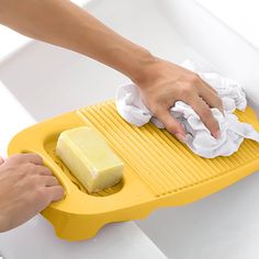 a person cleaning a bathtub with a yellow sponge and a cloth on the edge