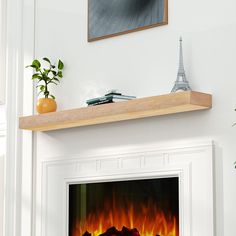 a white fireplace with an orange fire in the middle and a green plant on top