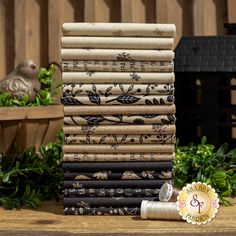 a stack of old books sitting on top of a wooden table next to some plants