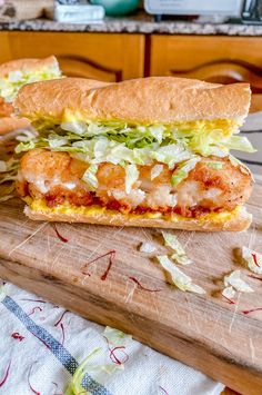 a sandwich with shrimp and lettuce on a cutting board next to a knife