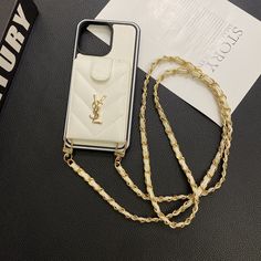 a white phone case sitting on top of a black table next to a gold chain