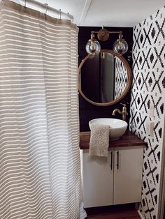 a bathroom with a sink, mirror and shower curtain