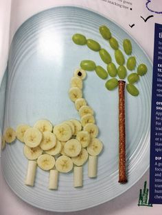 a plate with bananas, grapes and a giraffe made out of sliced banana slices