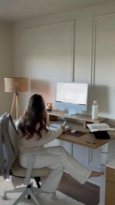 a woman sitting at a desk in front of a computer monitor, keyboard and mouse