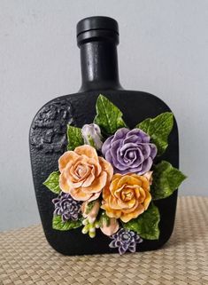 a black bottle with flowers painted on it