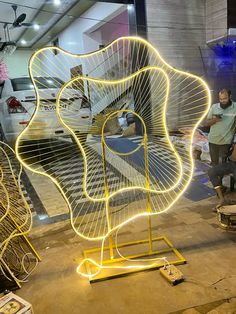 some people are standing around with lights in the shape of an abstract flower on display