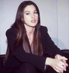 a woman sitting on top of a black couch next to a white wall in a room