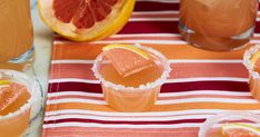 several glasses filled with drinks and garnished with orange slices on a striped table cloth