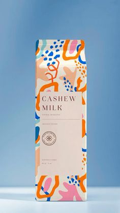 a carton of cashew milk on a blue background with an orange and pink pattern