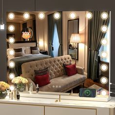 a couch sitting in front of a mirror with light bulbs on it's sides