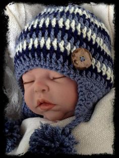 a newborn baby wearing a blue and white crochet hat with a wooden button