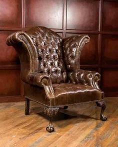 a brown leather chair sitting on top of a hard wood floor