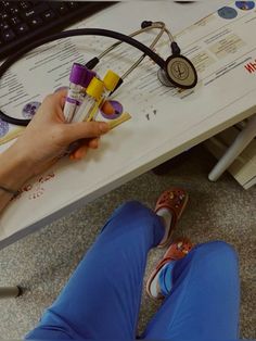 a person sitting at a computer desk with some pens and pencils in their hands