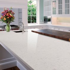 a white kitchen counter top with flowers in a vase next to the sink and stove