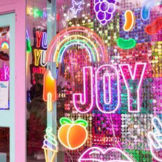 a store front window with neon signs and fruit on the windows display it's bright colors