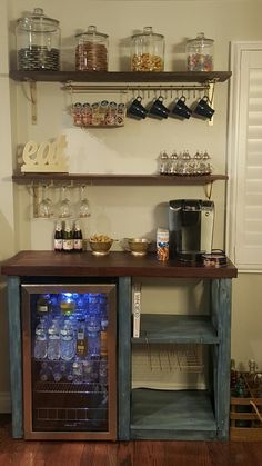 a small refrigerator is in the middle of a room with shelves and jars on it