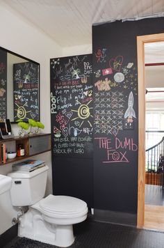 a bathroom with chalk writing on the wall and a toilet in the corner next to it