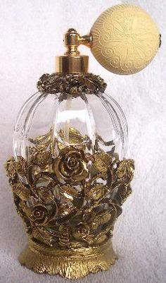 an antique perfume bottle with gold roses on it and a golden ball hanging from the top