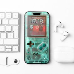 an iphone case with a gameboy design on it next to a keyboard and headphones