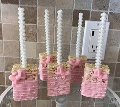 three little pink cakes with bows on them sitting in front of a light switch