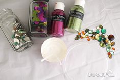 the contents of an assortment of nail polishes on a white table with beads and glass containers