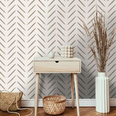 a white table with a basket and vase on it in front of a wallpapered background