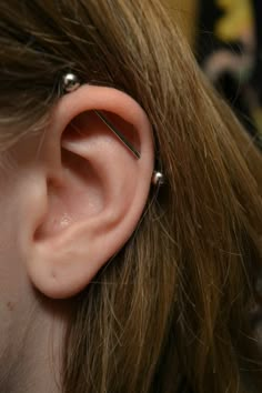 a woman's ear is shown with some piercings on it