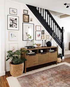 a living room with pictures on the wall and a stair case in front of it