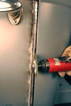 a man is using a tool to fix the door handle on a refrigerator freezer