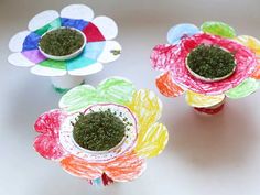 three paper flowers are sitting on a table with colored crayons in the center