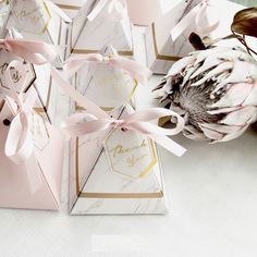 pink and gold place cards with bows on them sitting on a white table cloth next to an artichoke