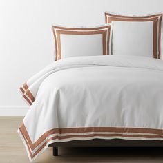 a bed with white and brown comforters on top of it in front of a wall