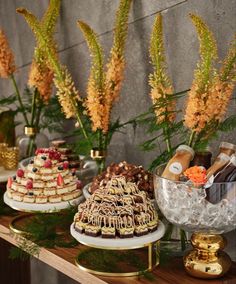 several desserts are displayed on small trays with flowers in vases next to them