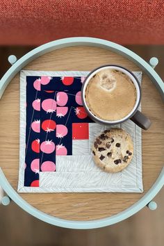 a cup of coffee sitting on top of a table next to a cookie