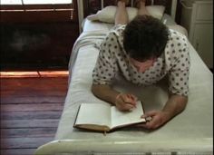 a person laying on a bed writing in a book