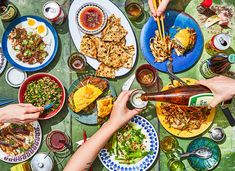 people are eating and drinking at an outdoor table with food on the plates, including salads