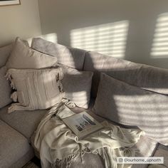 a couch with some pillows on top of it and a book laying on the floor