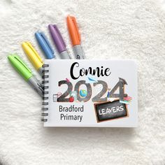 a notebook with markers and writing on it next to some other colored pen's