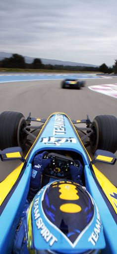 a blue and yellow race car driving down a track