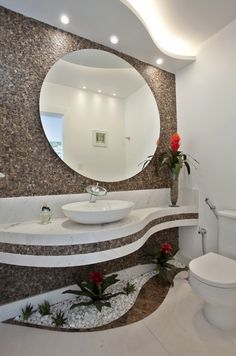 a bathroom with a round mirror above the sink and toilet in front of it, along with flowers on the floor