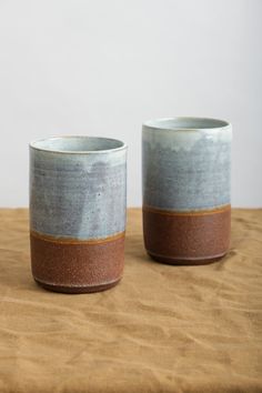 two cups sitting on top of a wooden table next to each other with one cup in the middle