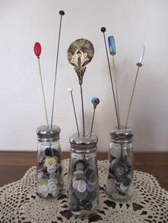 three glass jars filled with buttons on top of a doily