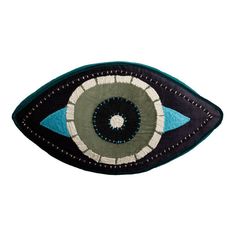 an embroidered eye patch with blue and green details on it's center, in front of a white background