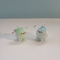 two small glass figurines sitting next to each other on a white counter top