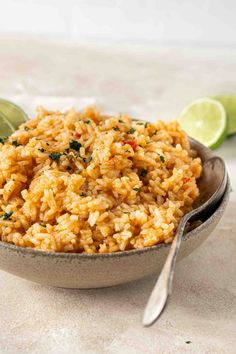 mexican rice in a bowl with limes and cilantro on the side, ready to be eaten