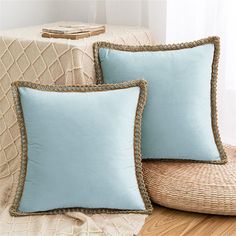 two blue pillows sitting on top of a wicker chair